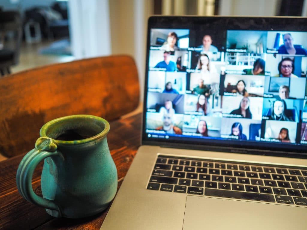 Picture of an online meeting on a computer screen with a cup of tea